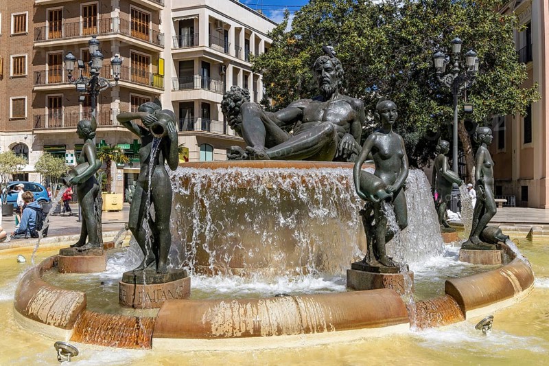Turia Fountain (Font Del Túria) with a large sculpture of the Turia Man in the centre, surrounded by many female sculptures in the Plaça de la Mare de Déu in the old town, Valencia, Autonomous Community of Valencia, province of Valencia, Spain