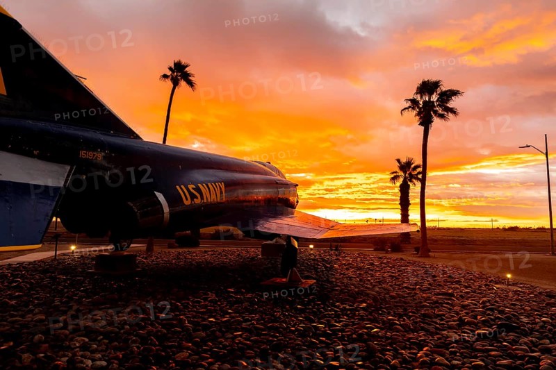 Dawn at Naval Air Field El Centro, CA: Sunlight paints vibrant hues across the sky, casting a mesmerizing rainbow over parked aircraft, creating a breathtaking spectacle