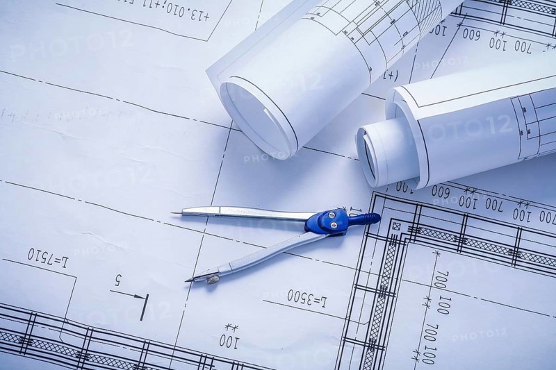 Vertical version compass and rolled blueprints close up