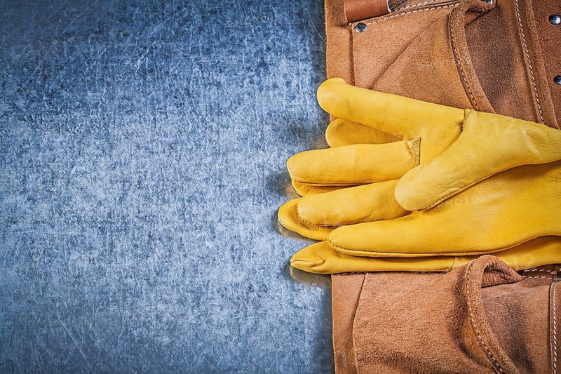 Pair of protective gloves toolbelt on metallic background construction concept