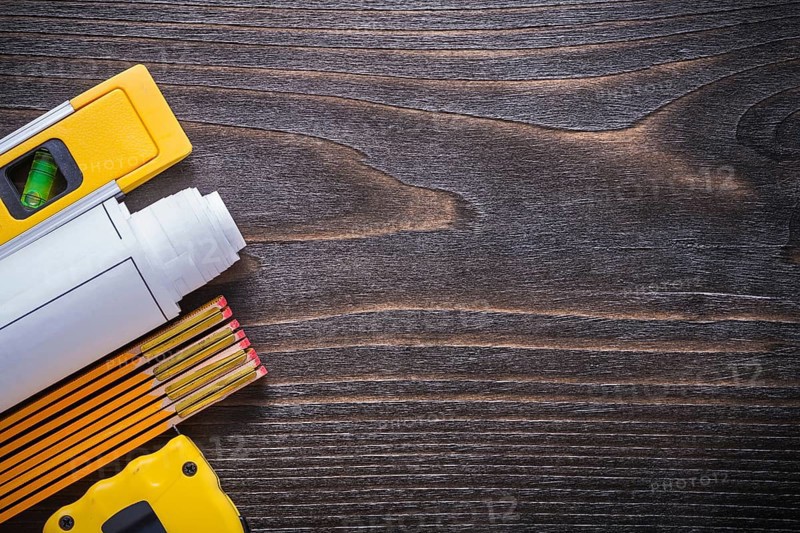 Blueprints construction level measuring tape and wooden meter on vintage wood board copy space image maintenance concept