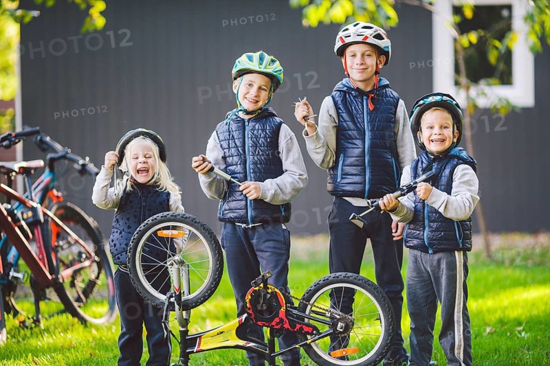 Children mechanics, bicycle repair. Happy kids fixing bike together outdoors in sunny day. Bicycle repair concept. Teamwork family posing with tools for repairing a bicycle in hands outside