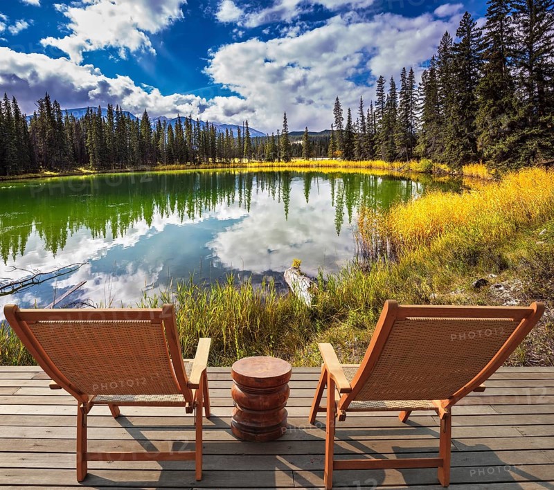 Two wooden deckchairs for tourists on ashore shallow round lake. Autumn day in Jasper National Park in the Rocky Mountains of Canada