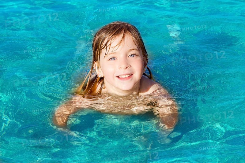Blond little girl swimming on turquoise beach in Ibiza