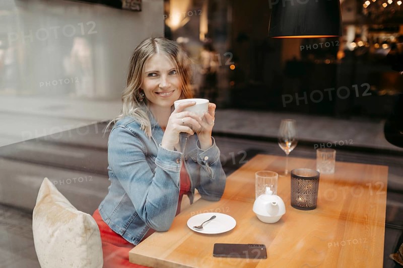 Blonde, attractive woman, 40+, sitting in a coffee house by the window