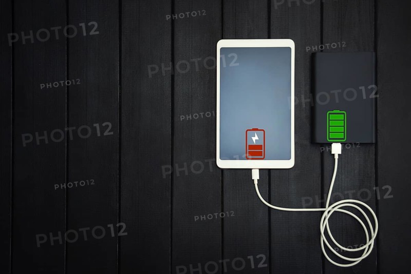 Power bank loads tablet PC, smartphone, isolated on wooden background. charging concept. free copyspace