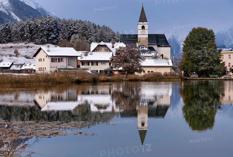 The church in the village Tarasp reflecting in the Taraspsee in the Swiss community Scuol in the canton of Graubunden
