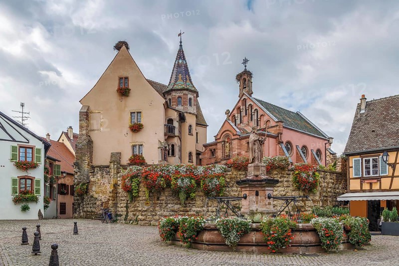 Main square with church and fountain with statue of pope Leo IX in Eguisheim, Alsace, France