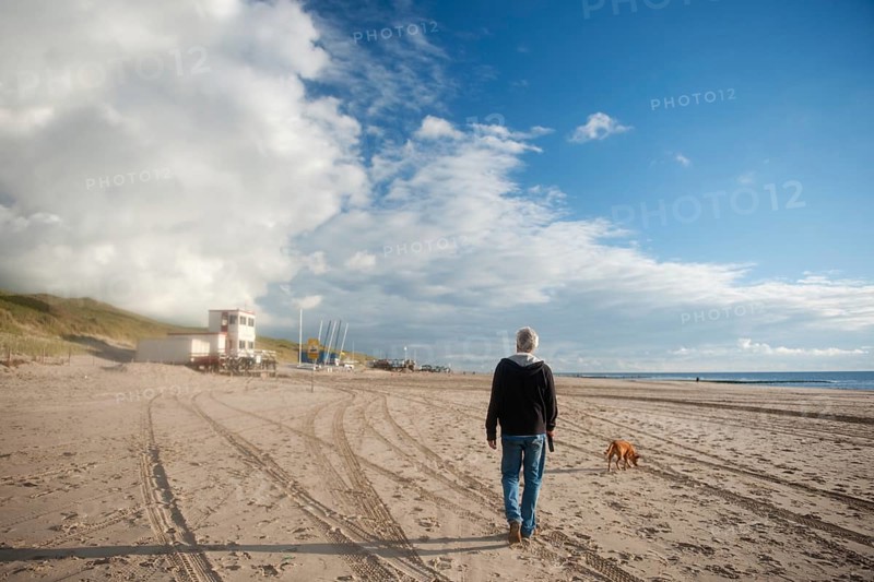 Elderly man is walking his dog at the beach