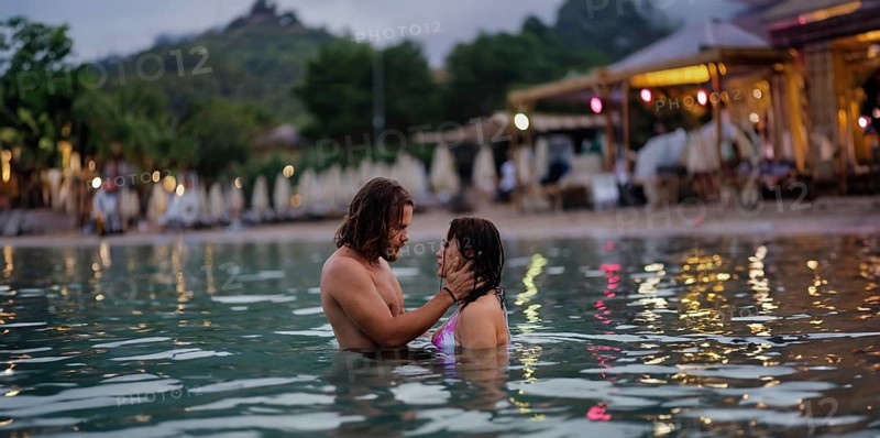 A couple in an intimate moment in the water near the beach during the evening