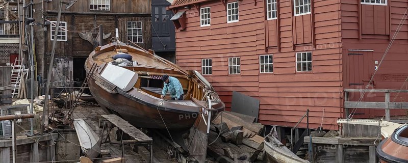 Spakenburg, The Netherlands - Fedbruary 19, 2021: Man inspecting historic ship at wooden ship wharf in the little pictoresque fishing village Spakenburg Bunschoten in Utrecht in the Netherlands, Bunschoten, Nederland