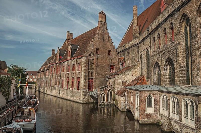 Old buildings on the canal bank, boats and sunny blue sky in Bruges. With many canals and old buildings, this graceful town is a World Heritage Site of Unesco. Northwestern Belgium