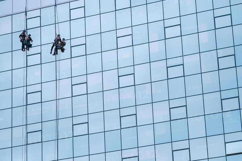 Two Worker Cleaning The Windows Of A High Rise Building Or Skyscraper, With Copy Space