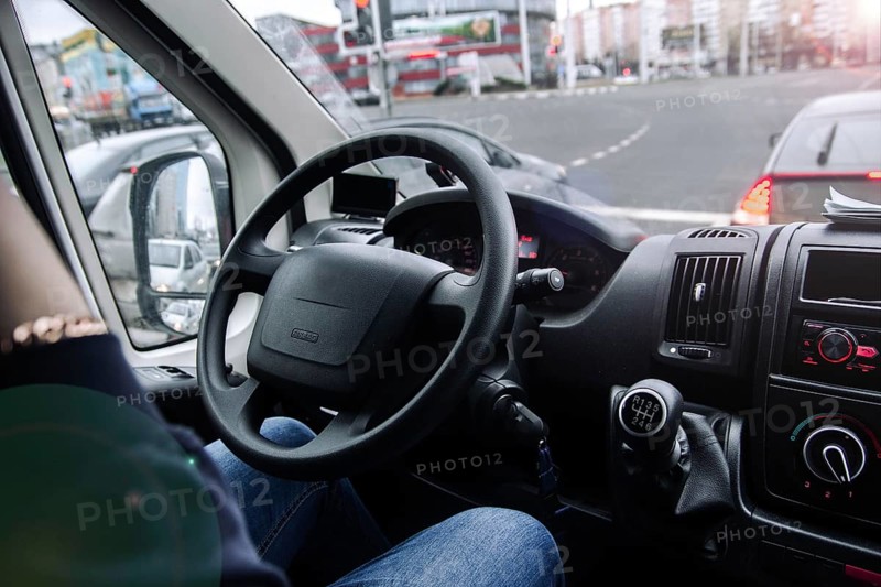 Inside a vehicle with a view of traffic and buildings through the windshield
