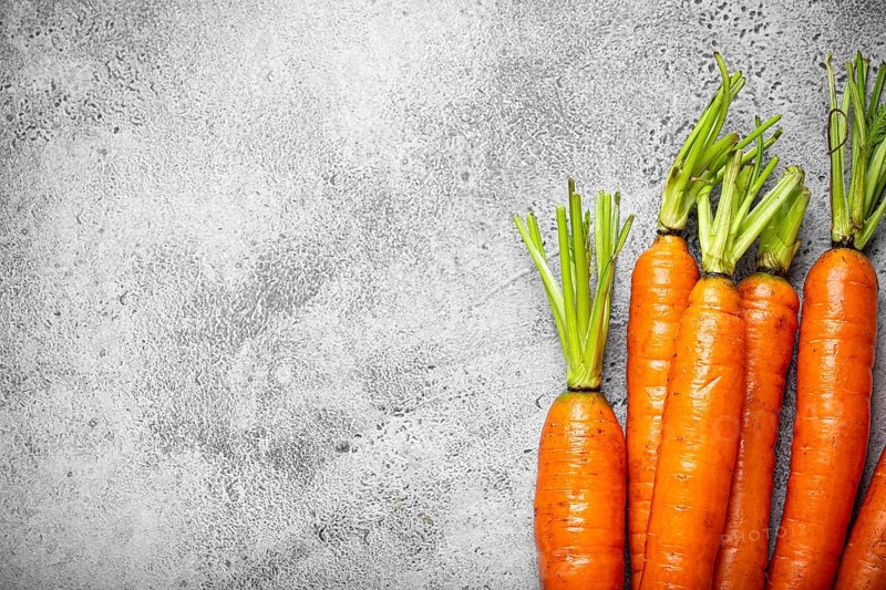 Fresh raw organic farmer carrots with leafs arranged on grey rustic stone background top view, healthy carrots in balanced nutrition and cooking concept, space for text, food photography, food photography
