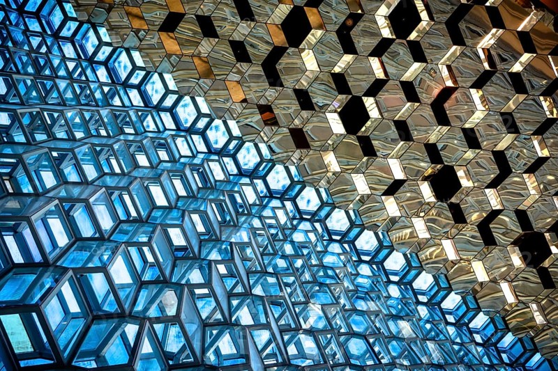 Compact geometric patterns in a glass architecture reflecting blue and gold tones, Harpa Concert Hall, Reykjavik, Iceland