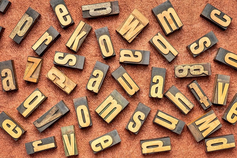 Random letters overhead background - vintage letterpress wood type (inverted image) against brown handmade bark paper