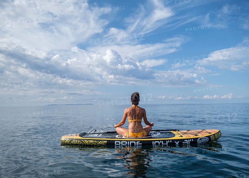 Woman practicing yoga on a surfboard under a dramatic sky, Estalella, coast of Llucmajor, Majorca, Balearic Islands, Spain