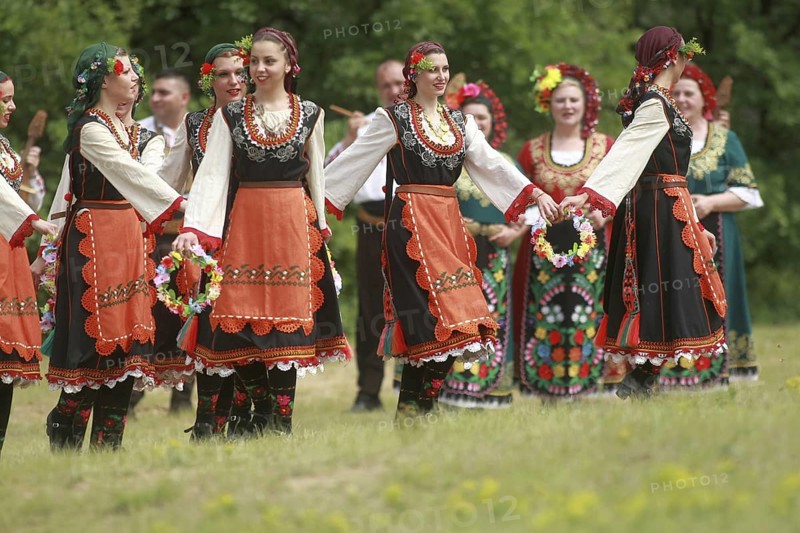 People in traditional costumes dance bulgarian horo a meadow near the village of Varvara