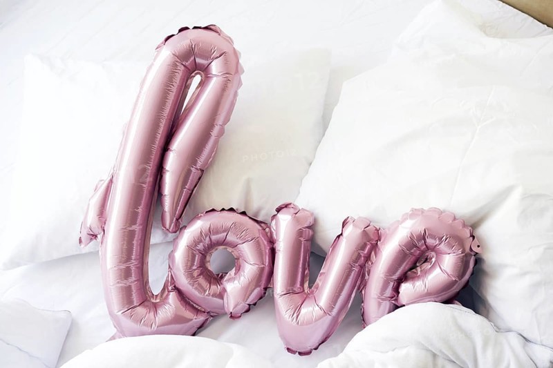 Large pink inflated letters LOVE on linens on the bed. The trend for Valentine's Day