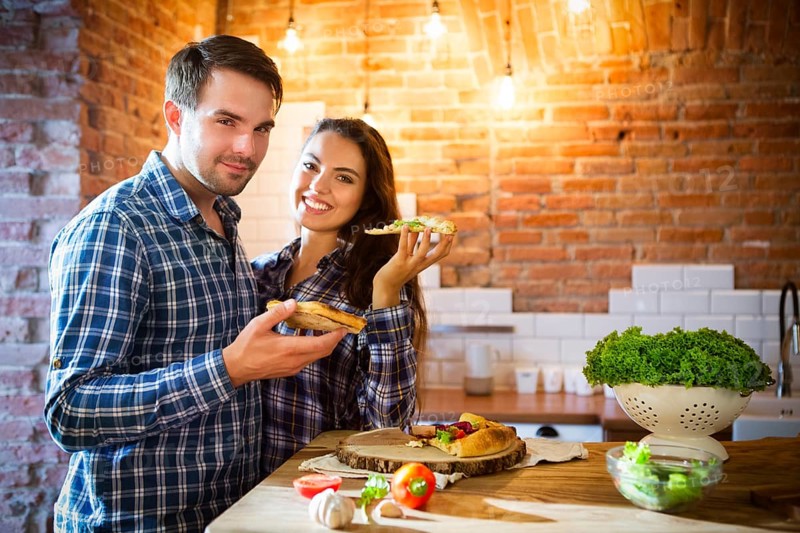 Young smiling couple eating homemade pizza together at kitchen
