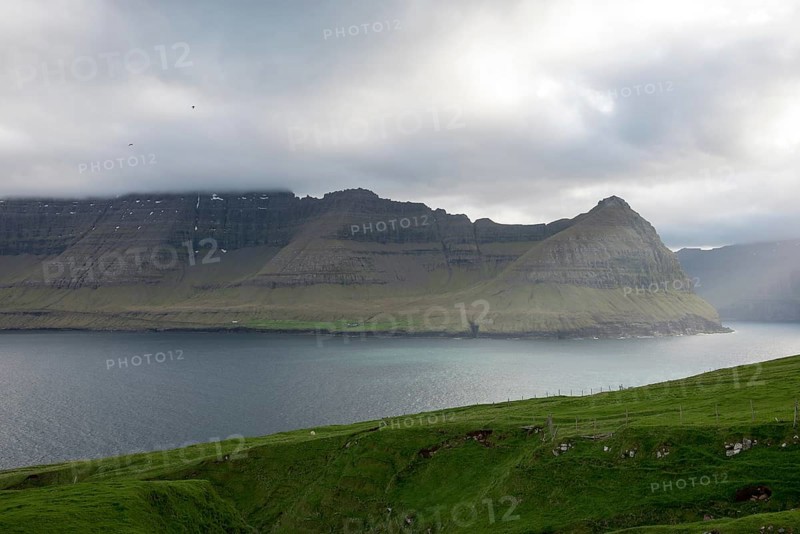 Typical landscape on the Faroe Islands, with green grass and rocks as seen from Vidareidi, Vidareidi, Faroe Islands