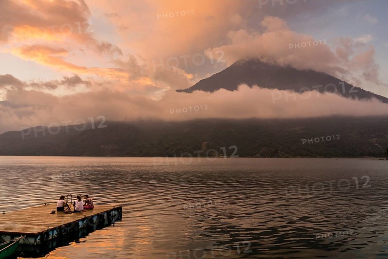 Tourists on a mooring enjoying the sunset, Lake Atitlan and San Pedro volcano, Santiago Atitlan, Sololá department, Guatemala
