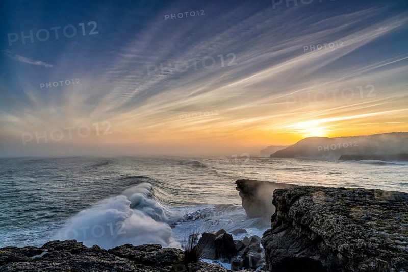 A view of huge storm surge ocean waves crashing onto shore and cliffs at sunrise