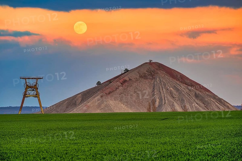 A view of an overburden heap in saxony-anhalt with a winding tower at moonrise