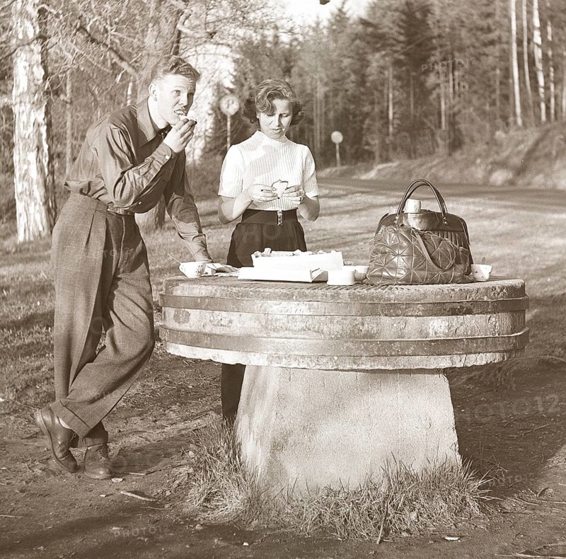 Lifestyle in the 1950s. A young couple has stopped to have a coffee and a sandwich by the roadside. An old millstone makes a good table for the picnic. Sweden 1952 Kristoffersson Ref BF76-4