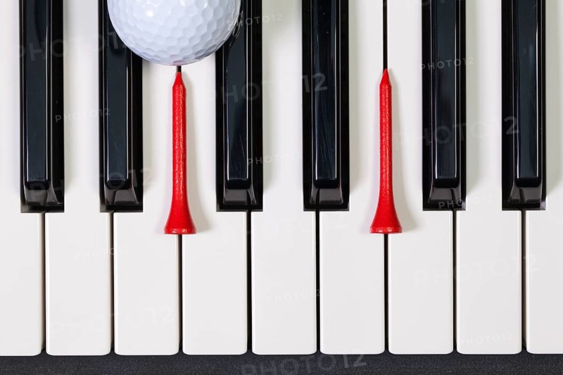 Virtuosic game - Piano keyboard and different golf balls and wooden tees