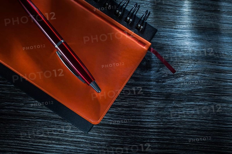 Pocketbooks pen on vintage wooden board top view