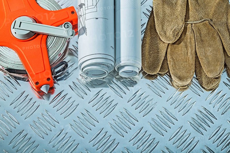 Blueprints safety gloves measuring tape on fluted metal sheet