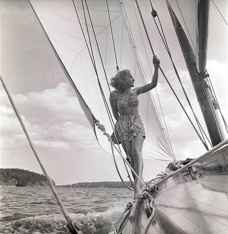 1940s sailing boat. A young woman is aboard a fashionable sailing boat and is standing on deck when it cruises forward with wind in the sails. She is wearing a typical 1940s two piece bathing suit. Sweden 1946 Photo Kristoffersson ref AC100-2-4