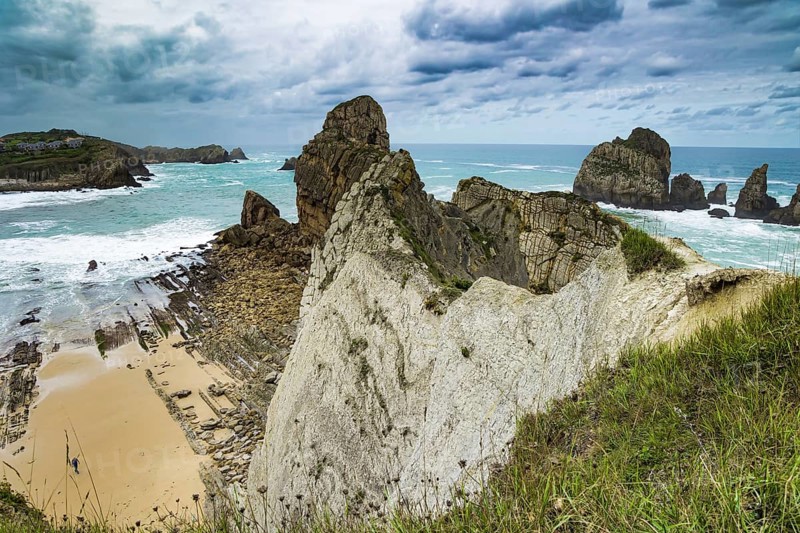 Cantabria. Noon on the beach of Playa di Arnia, Spain. Windy stormy day on the Atlantic coast. Rocky picturesque ocean coast. Powerful surf waves with a foam crest
