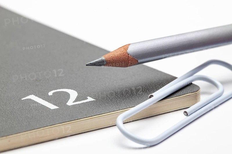 Organizer for the month of December, silver pencil and white paperclip on the white table