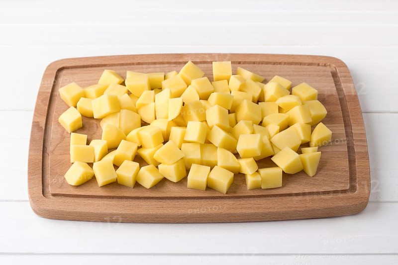 Food, Wooden board with fresh diced potatoes on a light gray background. Stage of cooking vegetable stew