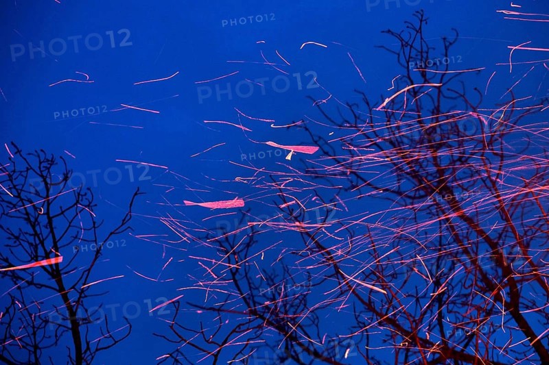 Spinning sparks leave their trajectory as they swirl upwards in the dark blue evening sky. Landscape format. Swirling sparks leave behind their red glowing flight tracks on the whirling ascent into the dark blue evening sky. Horizontal format