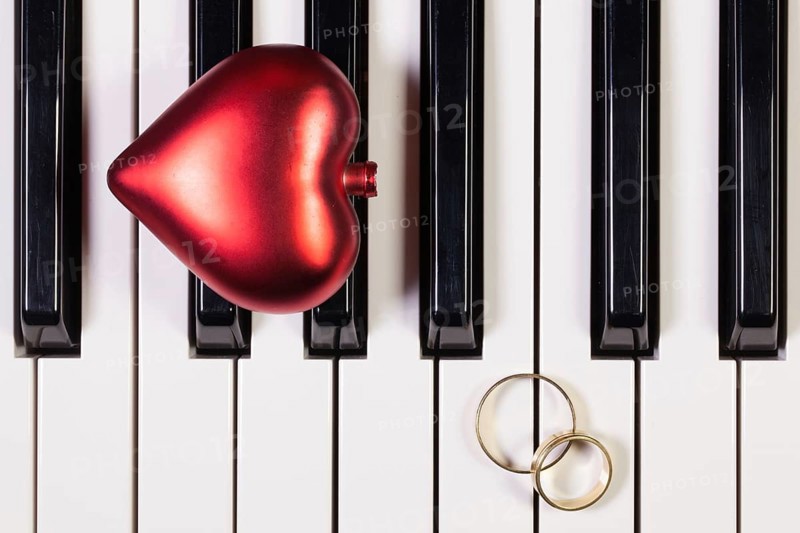 Detail of piano keyboard, red heart and wedding rings
