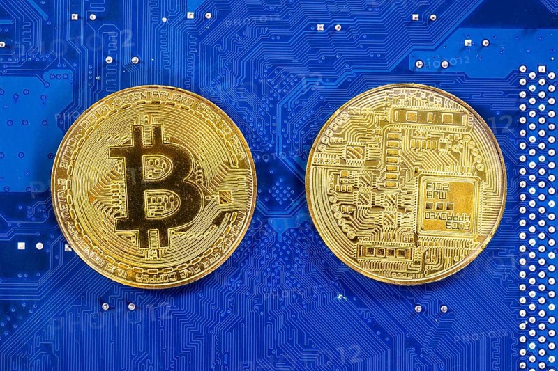 Virtual cryptocurrency money Bitcoin golden coins on a computer printed circuit board PCB. The future of money. Computational equipment. Blue mother board. Shot directly from above