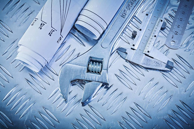 Blueprints vernier scale caliper monkey spanner on channeled metal background construction concept