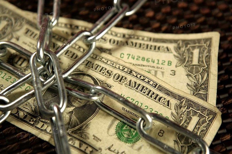 One Dollar notes in chains studio shot over brown background