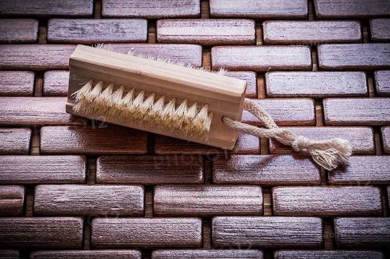 Wood scrubbing brush on textured wooden matting top view healthcare concept