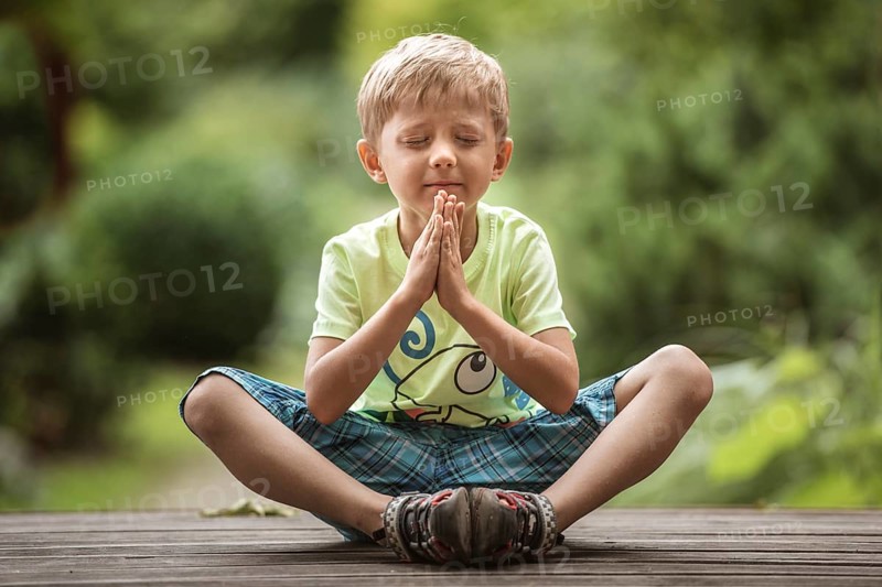 5-6 years old boy meditates in the park