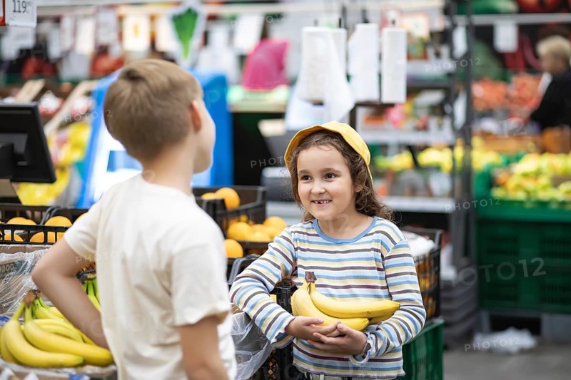 Kids little cute girl and teenager boy shopping for fresh organic fruits bananas and vegetables in supermarket