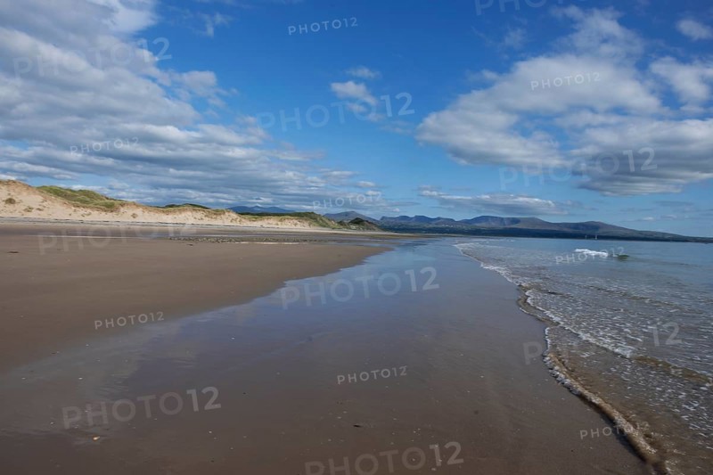 Beach and dunes with calm sea, in the background the mountains of Snowdonia National Park, Ynys Llanddwyn, Newborough, Anglesey, Wales, United Kingdom