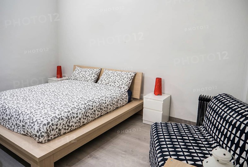 Small cozy bedroom interior furnished with comfortable soft bed and chair in contemporary apartment
