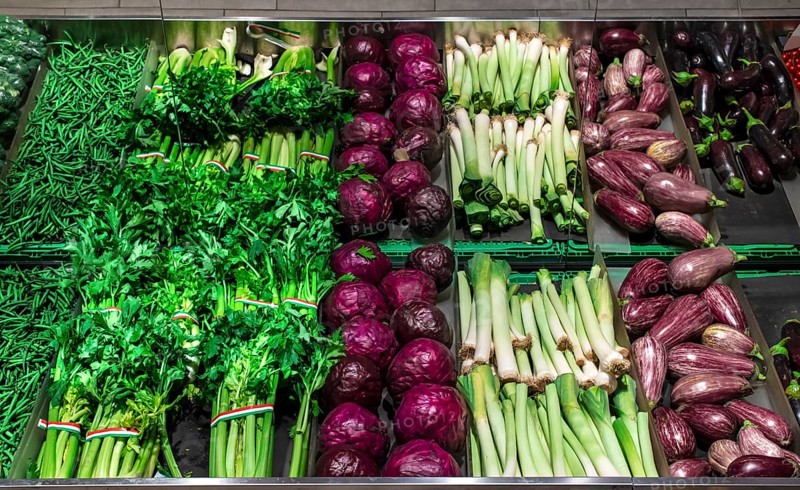 Vegetables on shelf in supermarket. Celery, eggplant, cabbage and beans