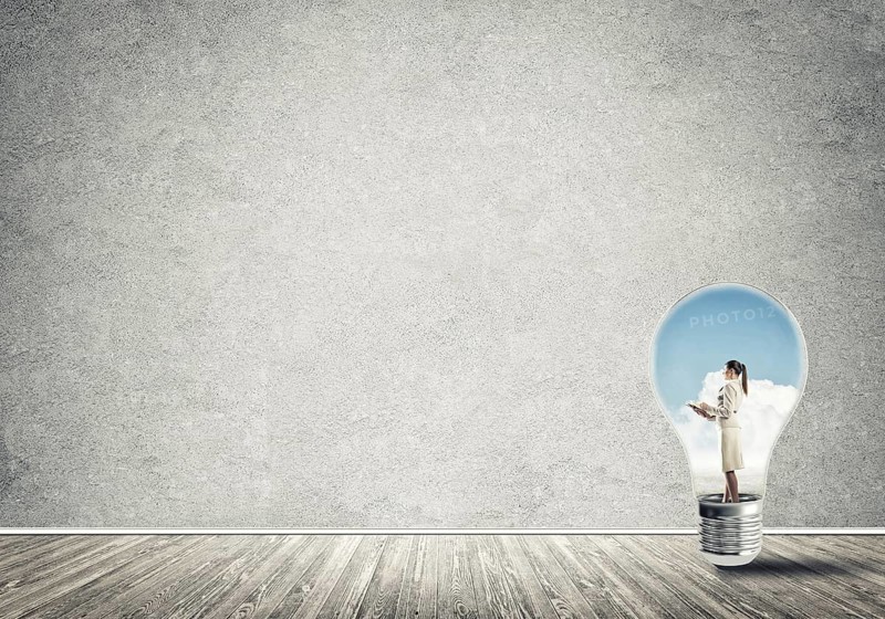 Businesswoman inside of light bulb in empty concrete room