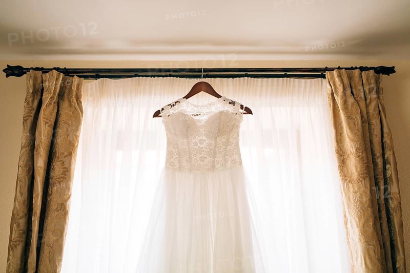 The bride's dress hangs on the cornice on the window